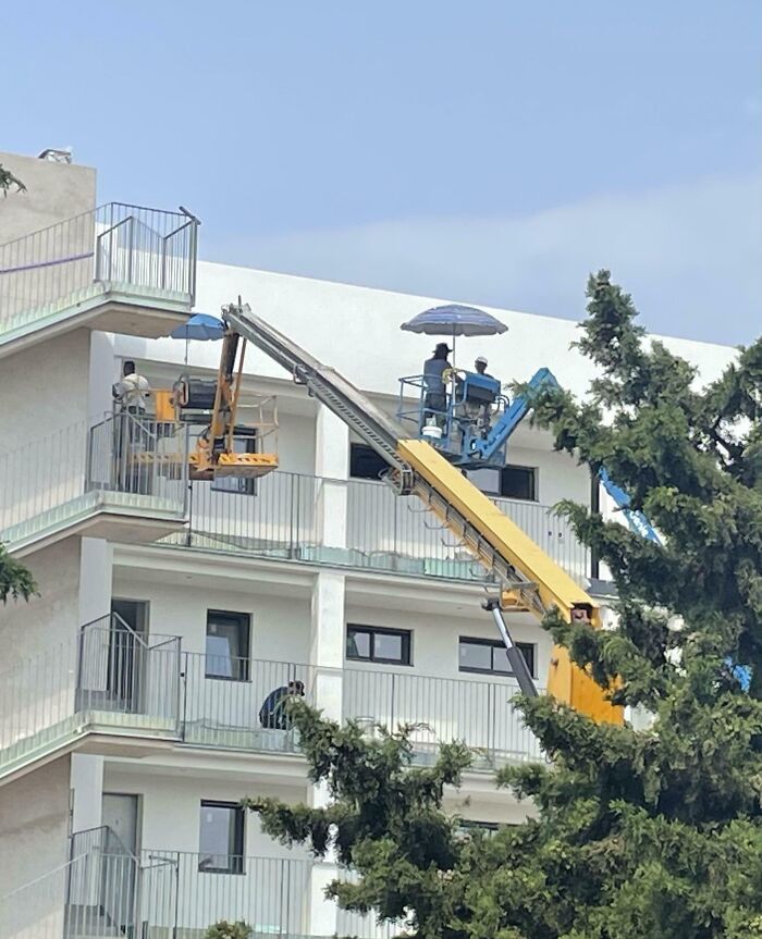 Builders in Spain Put Parasols on Their Cherry Pickers Because Sunburn is No Fun
