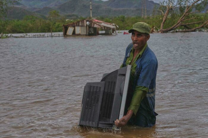 Man Hauling TV from Flooded House After Hurricane Melissa