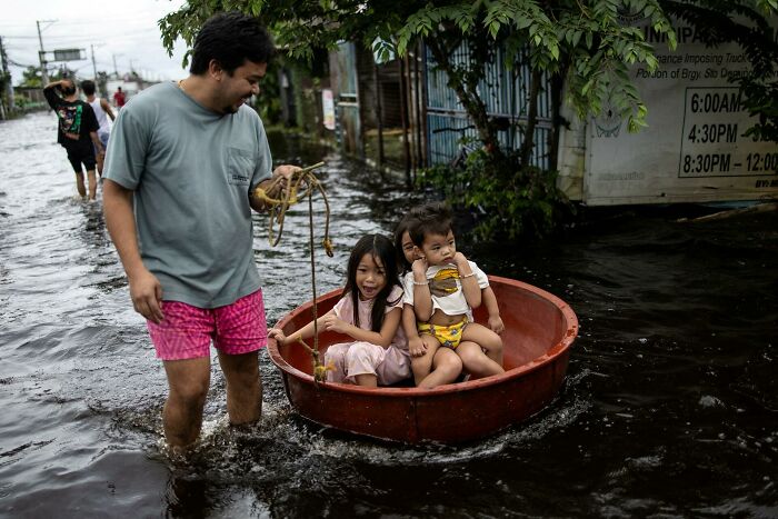 Kids Riding in a Basin Through Flooded Streets in the Philippines