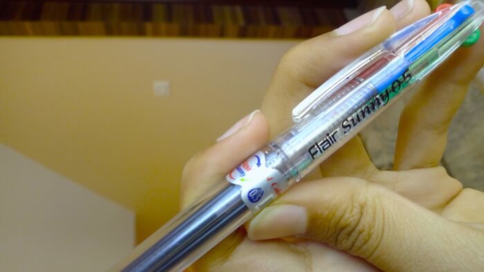 Trying to press all colors on a color-changing pen at once, hoping to write a rainbow in one go.