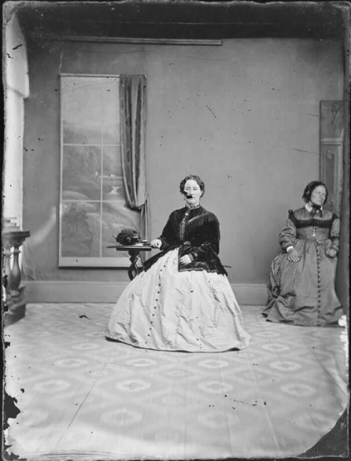 Two Women Sitting Apart During A Studio Shoot: The Mystery Of The Woman Not Looking At The Camera