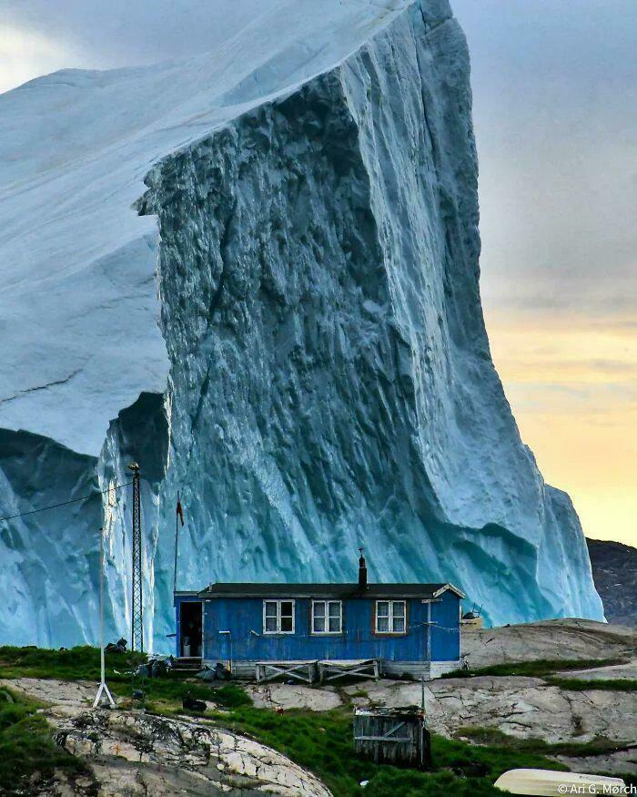 An Iceberg Cruises Near A Greenland House—Yikes, That’s Huge!